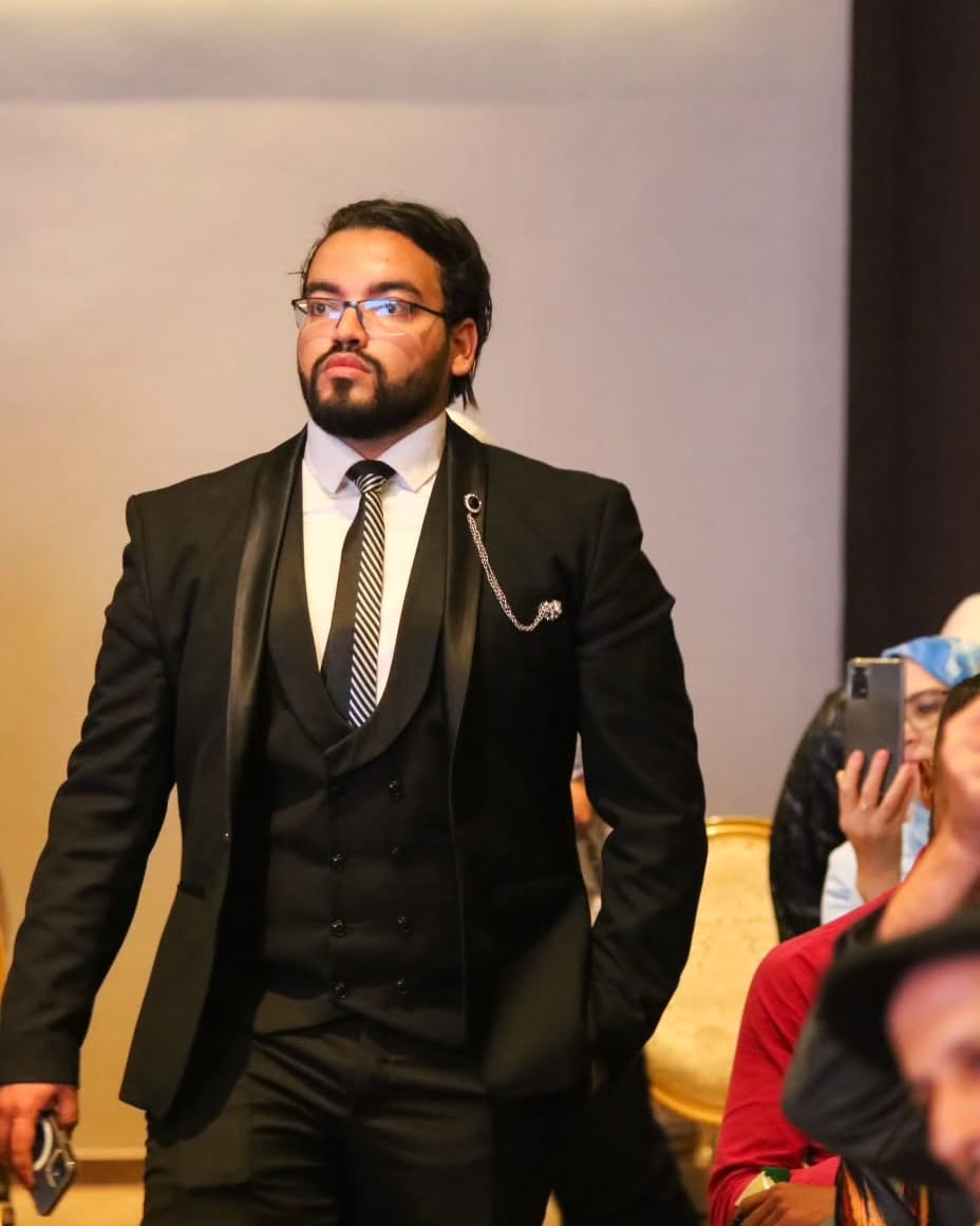 Mohamed Amine Missaoui standing in a formal black suit at a professional event, confident executive posture