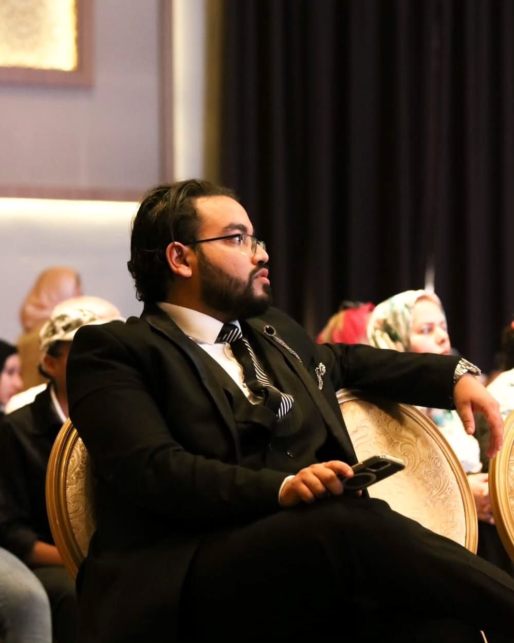 Mohamed Amine Missaoui seated in a formal black suit at a professional event, executive presence